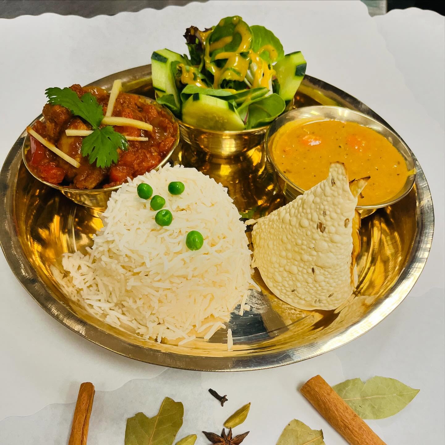 A complete traditional Nepali meal platter featuring a variety of dishes, including rice, lentils, vegetables, and pickles.